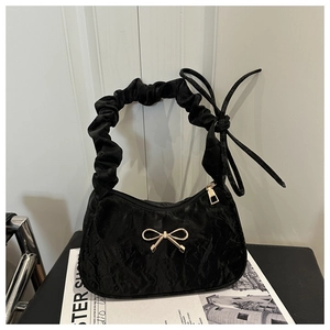 Detailed shot of black ruched shoulder bag with a gold bow buckle and scrunchie strap