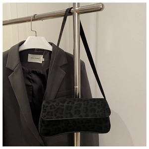 Detail of black leopard print shoulder bag with suede texture hanging on a metal rack