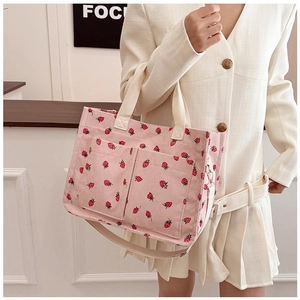 Detailed shot of pink corduroy tote bag with strawberry print and front dual pockets