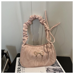 Detail of pink silk-texture bag with scrunchie handle and gold bow accent