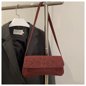 Detail of dark red leopard print suede underarm bag hanging on a metal hanger