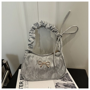 Detail of silver metallic handbag with bow buckle and ruched cloud handle design