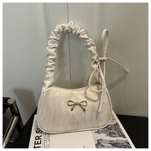 Macro detail of creamy white scrunchie bag handle and golden metal bow buckle