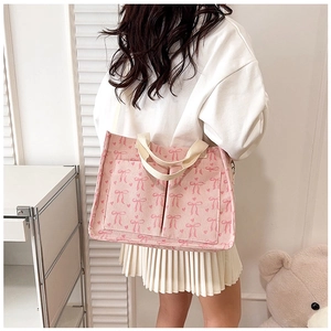 Pink corduroy tote bag with bow print shown on model in a minimalist setting