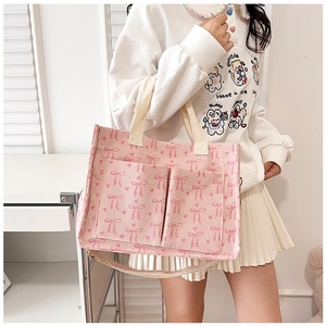 Detailed view of pink corduroy tote bag featuring bow prints and dual front pockets
