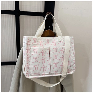 Detail of corduroy tote bag with pink bow patterns and adjustable shoulder strap