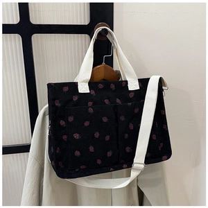 Detail of black corduroy tote bag with pink strawberry prints and double front pockets