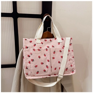 Detail of pink corduroy tote bag with red strawberry pattern and functional front pockets