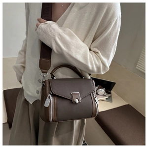 Detail of dark brown leather handbag with wide woven strap and silver buckle hardware