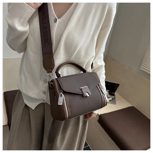 Close-up of brown textured leather handbag with silver lock and classic logo strap