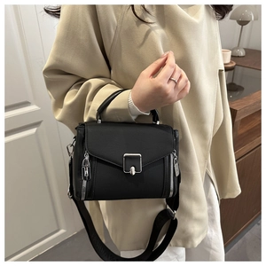 Detail of black pebbled leather crossbody bag with silver hardware and wide logo strap