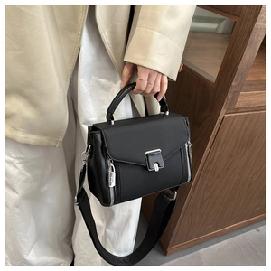 Detail of black pebbled leather handbag with silver lock and wide lettered shoulder strap