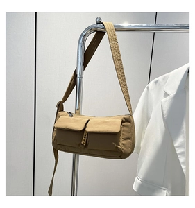 Detail of khaki nylon shoulder bag featuring utility pockets and padded strap hanging