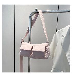 Detail of light pink nylon cylinder bag with functional pockets and wide strap