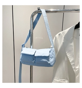 Close-up of a light blue nylon shoulder bag with dual front utility pockets and wide strap