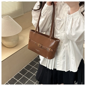 Detail of the brown tote bag with decorative metal buckle and premium faux leather texture