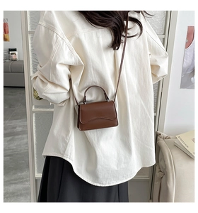 Brown mini leather satchel bag with scalloped flap shown in a crossbody style on model
