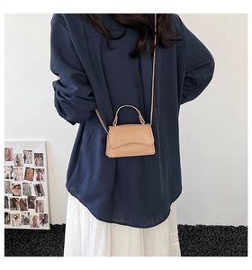 Detailed view of mini beige leather crossbody bag with elegant wavy flap and slim strap