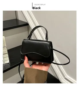 Detail of a chic black leather crossbody bag with wave-shaped flap and top handle