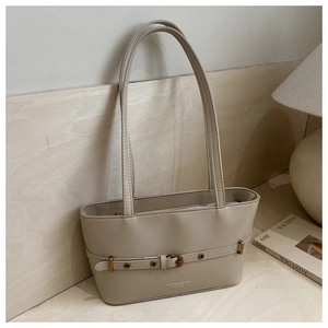 Detail of cream leather tote bag featuring buckle strap accents and vintage metal eyelets