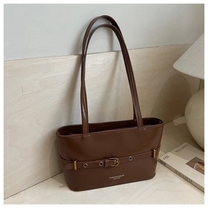 Detail view of brown faux leather tote bag with decorative metal buckle and logo print