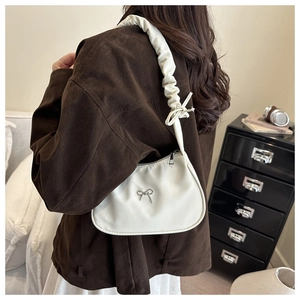 Detalle del bolso de hombro plisado blanco con hebilla de lazo metálica y cinta chic
