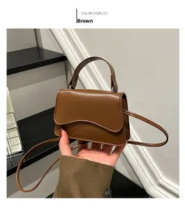 Detailed close-up of brown PU leather handbag featuring wave-edge flap and top handle