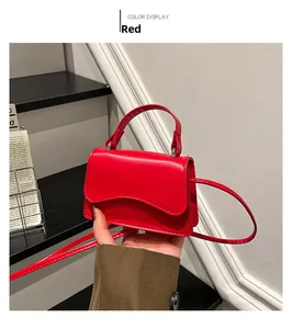 Detail of red mini crossbody bag with wave-edge flap and detachable shoulder strap