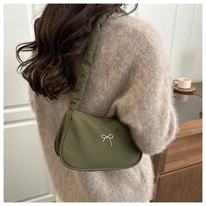 Détail d'un sac croissant vert foncé avec nœud métallique argenté et bandoulière plissée