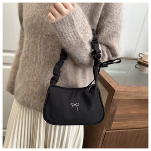 Detalle de bolso medialuna negro con lazo plateado y diseño de correa fruncida chic