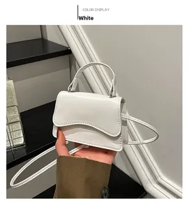Close-up of a white mini handbag featuring a unique wavy edge flap and leather handle