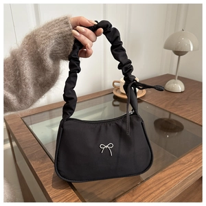Détail du sac croissant noir avec anse plissée et nœud décoratif en métal argent
