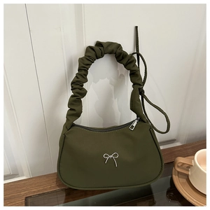Détail du sac croissant vert olive avec poignée froncée et pendentif nœud argenté sur verre