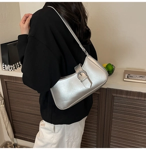 Detail einer silbernen Schultertasche mit Schnallen-Design an einem weiblichen Model