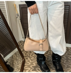 Detail of beige PU leather underarm bag with silver metal buckle strap and slim handle
