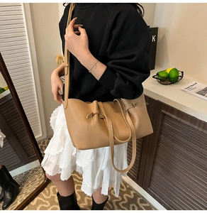 Detailed view of camel drawstring bucket bag with handle and adjustable shoulder strap
