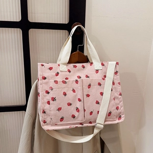 Pink corduroy tote bag with strawberry print, adjustable strap, and front pockets