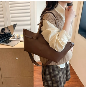 Close-up of a large dark brown leather tote bag with side knot detail on a model