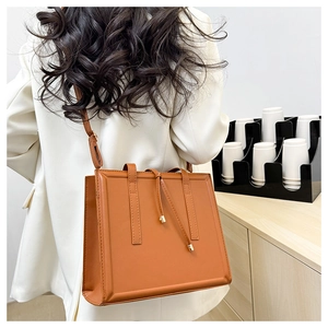 Détail d'un sac à bandoulière en cuir caramel avec détails dorés et cordon de serrage