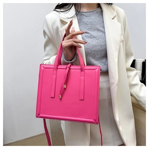 Détail du sac à main carré en cuir fuchsia avec finitions métalliques sur costume blanc