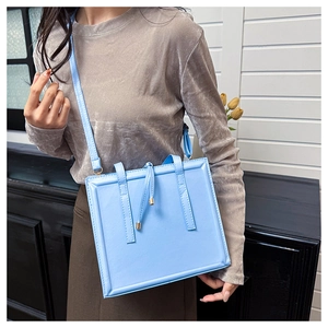 Vue détaillée d'un sac bandoulière bleu ciel avec sangles verticales et cordon de serrage