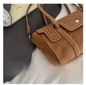 Detail shot of brown vintage handbag featuring contrast white stitching and silver buckle