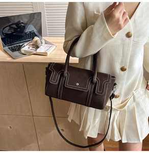 Détail d'un sac à main en cuir marron foncé avec coutures contrastées et boucle en métal