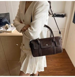 Detail of vintage brown suede handbag with white stitching and silver metal buckle