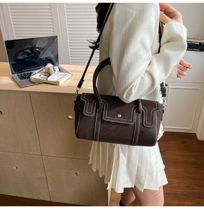 Detail view of dark brown crossbody bag with contrast white stitching and top handle