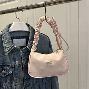 Sac croissant rose avec poignée froncée et nœud métallique sur veste en jean