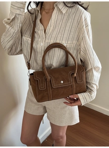 Detail view of brown vintage handbag featuring contrast stitching and silver metal buckle