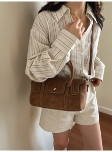 Detailed view of a vintage brown crossbody bag with metal lock and stitching accents