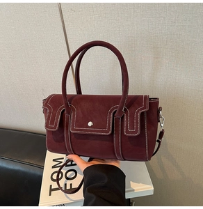 Macro detail of bordeaux leather handbag with contrast white stitching and silver buckle