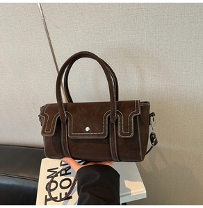 Détail du sac à main en cuir marron foncé avec surpiqûres et bandoulière réglable